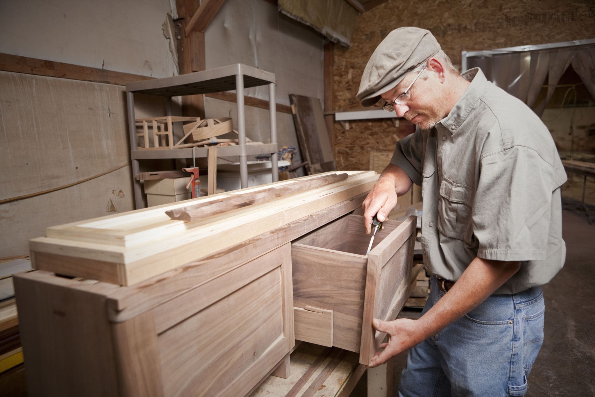 Man working on a wooden cabinet drawer.